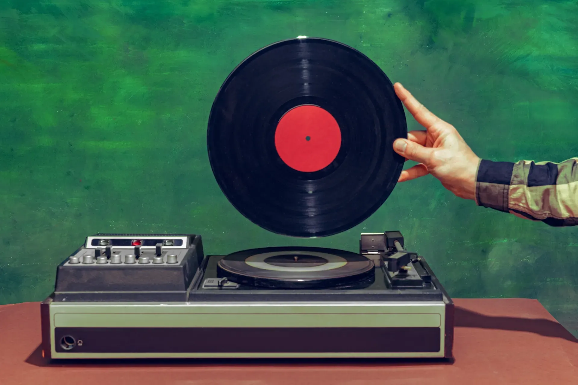 Man holding a vinyl record above a turntable 