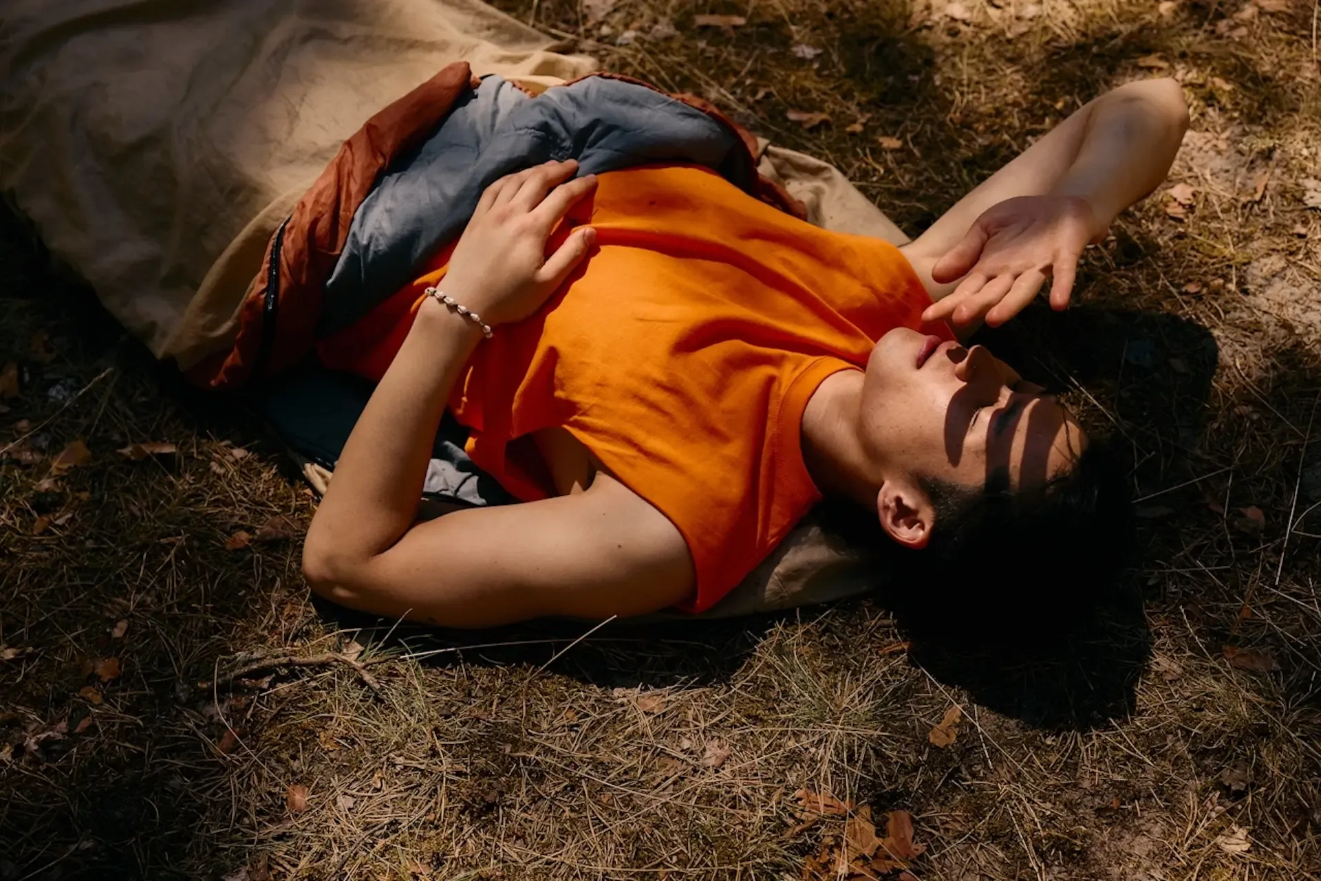 Person laying on the ground and shielding their eyes from the sun