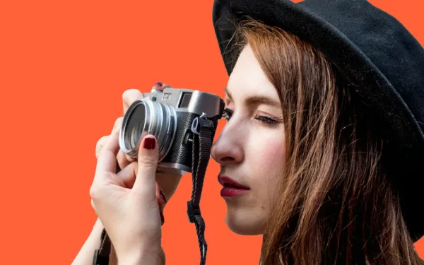 Woman in a hat taking a photo with a camera
